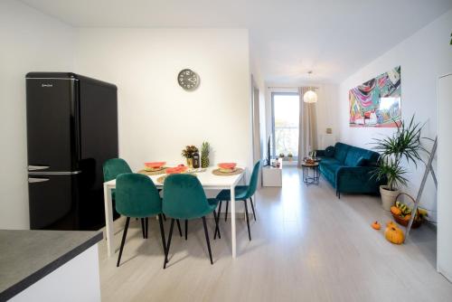 a kitchen and living room with a table and green chairs at Maya's Apartments in Gdańsk