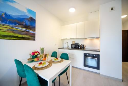 a kitchen with a white table and blue chairs at Maya's Apartments in Gdańsk