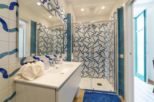 a bathroom with a white sink and blue and white tiles at REGINNA LIGHTHOUSE in Maiori