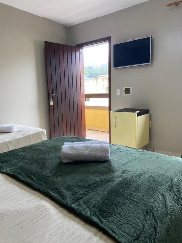 um quarto com duas camas com um cobertor verde na cama em Pousada Santa Terezinha em Garopaba