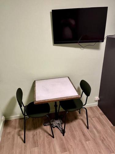 d'une table avec deux chaises et d'une télévision à écran plat. dans l'établissement Brouettes 3 : Studio Mezzanine, à Rouen