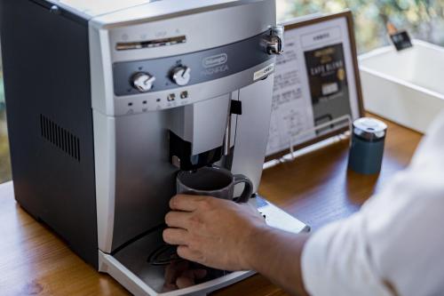 a person is holding a cup in a coffee machine at 漫步月眉民宿 in Guanshan