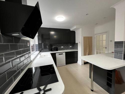 a kitchen with black cabinets and a white counter top at Springfield House- Near Newcastle Centre, Hospital and Keele University! in Stoke on Trent