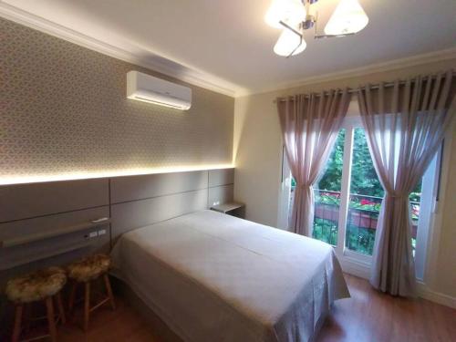 ein Schlafzimmer mit einem weißen Bett und einem Fenster in der Unterkunft Apartamento novo centro de Canela in Canela