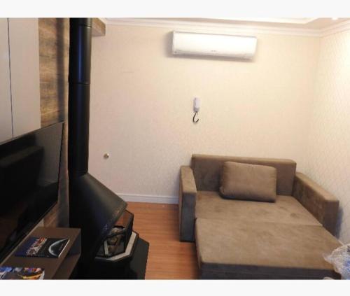 ein Wohnzimmer mit einem Sofa und einem TV in der Unterkunft Apartamento novo centro de Canela in Canela