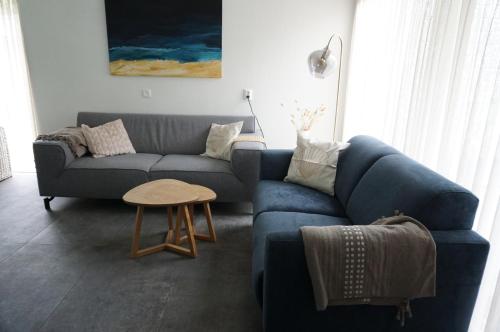 a living room with a blue couch and a table at Kustverhuur, Park Schoneveld, Zeester 46 in Breskens
