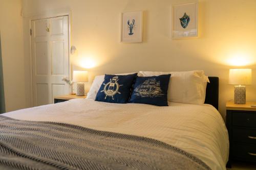 a bedroom with a bed with pillows and two lamps at Dartmouth Town Centre 2 bedroom stylish apartment is perfect for families and couples with a happy & homely feel being only 30 meters from the sea but set back & quiet with everything on the doorstep a gorgeous place to explore the Devon beaches 5 star FB in Dartmouth