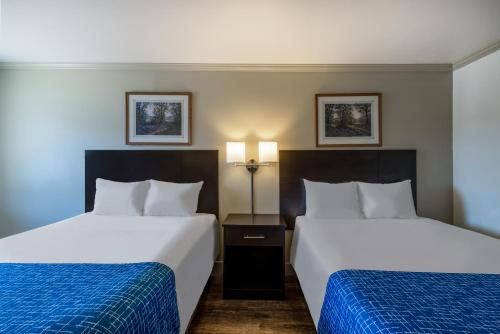 a hotel room with two beds with blue sheets at Travelodge by Wyndham Livingston in Livingston