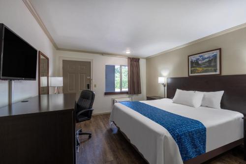 a hotel room with a bed and a desk and a tv at Travelodge by Wyndham Livingston in Livingston