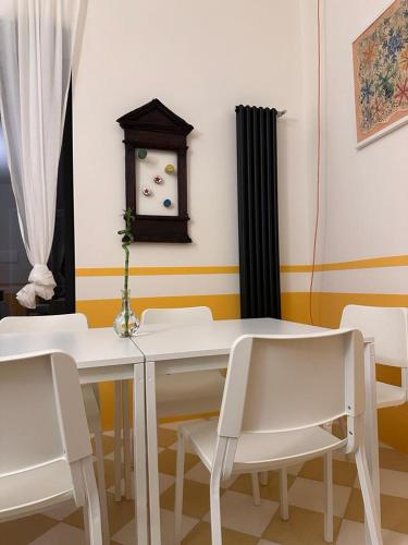 a dining room with a white table and chairs and a clock at Le Case di LuVi in Nola
