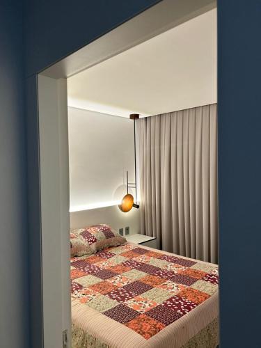 um quarto com uma cama com uma colcha em Apto Novo Studio Nature a 50 m da praia em Torres