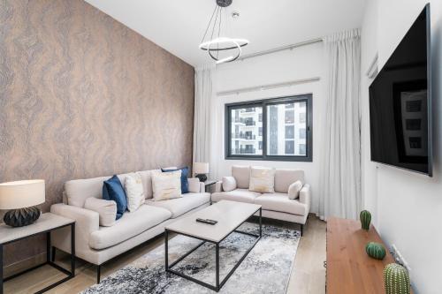a living room with a couch and a table at Nasma Luxury Stays - Home-Style 2BR Apartment with a Balcony View in Dubai