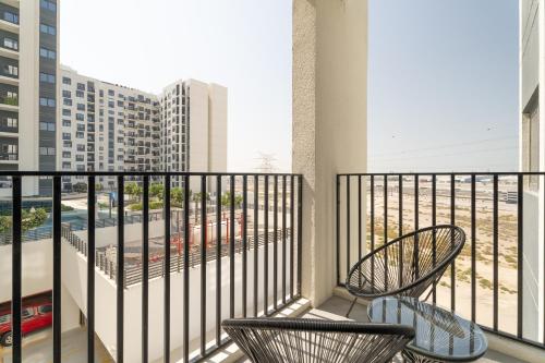 two chairs on a balcony with a view of a city at Nasma Luxury Stays - Home-Style 2BR Apartment with a Balcony View in Dubai