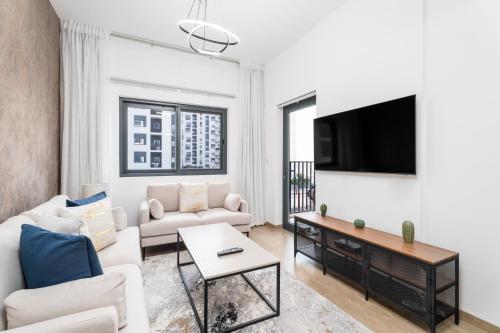 a living room with white furniture and a flat screen tv at Nasma Luxury Stays - Home-Style 2BR Apartment with a Balcony View in Dubai