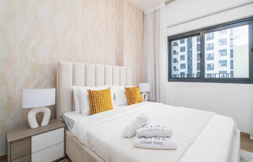 a bedroom with a large white bed with yellow pillows at Nasma Luxury Stays - Home-Style 2BR Apartment with a Balcony View in Dubai