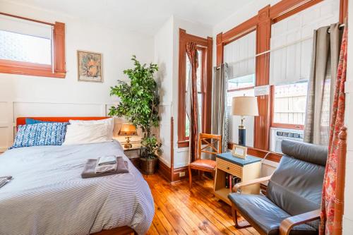 1 dormitorio con 1 cama y 1 silla en Step Back in Time Charming Victorian with Modern Amenities en Homestead