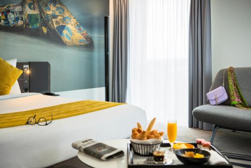 a hotel room with a bed and a tray of food at Novotel Paris Coeur d'Orly Airport in Orly