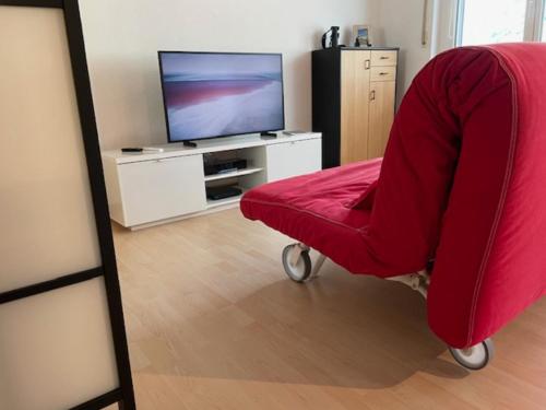 uma sala de estar com uma cadeira vermelha e uma televisão em Marmotta 13 em Leukerbad