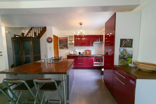 una cocina con armarios rojos y una isla de cocina con taburetes en La Maison de Milly - Calme & Cosy, en Milly-la-Forêt