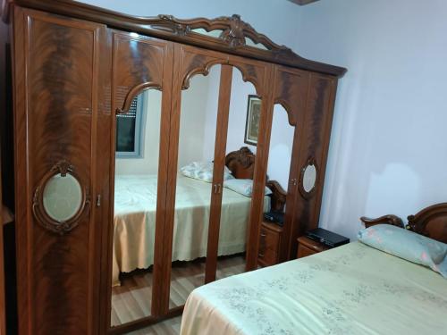 a bedroom with a wooden bed and a mirror at FETAHU HOSTEL in Poliçan