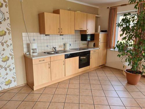 a kitchen with wooden cabinets and a tile floor at Ferienwohnungen Meyerhof_ 55116 in Filsum