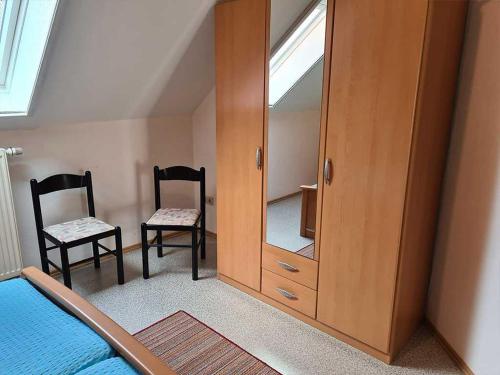 a bedroom with a large mirror and two chairs at Ferienwohnungen Meyerhof_ 55116 in Filsum