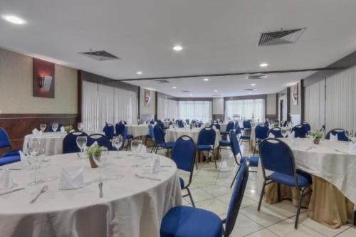 une salle de banquet avec des tables blanches et des chaises bleues dans l'établissement Iate Plaza Flat 613, à Fortaleza