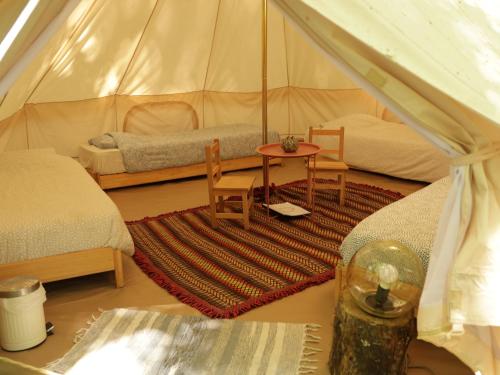 una camera con 2 letti e un tavolo in una tenda di Eco-Hostel Quinta das Relvas a Branca