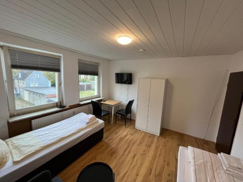 Zimmer mit 2 Betten, einem Tisch und einem Kühlschrank in der Unterkunft Monteurwohnungen nähe Holsten Galerie in Neumünster