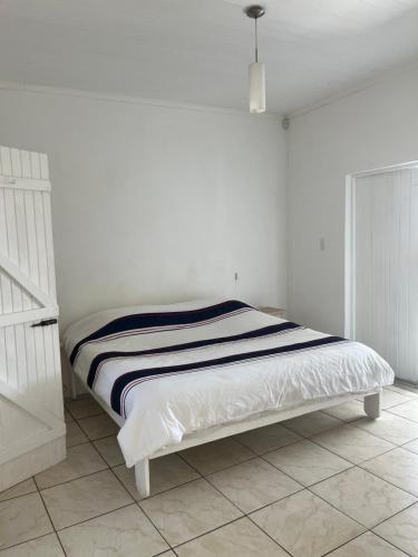 Bett in einem weißen Zimmer mit einer weißen Wand in der Unterkunft Black Pearl Wine Cottage in Suider-Paarl