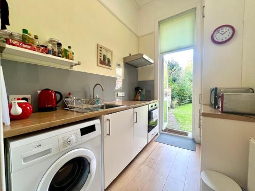 uma cozinha com uma máquina de lavar roupa e um lavatório em Beautiful Spacious Ground Floor Newington flat em Edinburgo