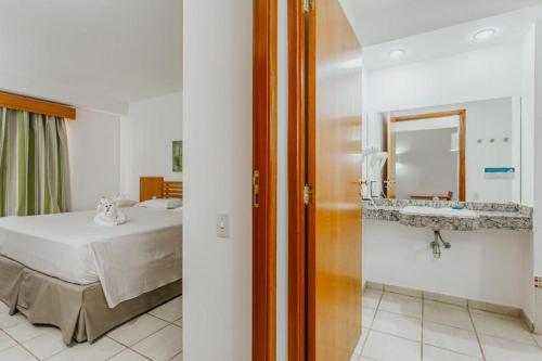 a bedroom with a bed and a mirror and a sink at Rio Quente Resorts - Hotel Giardino in Rio Quente