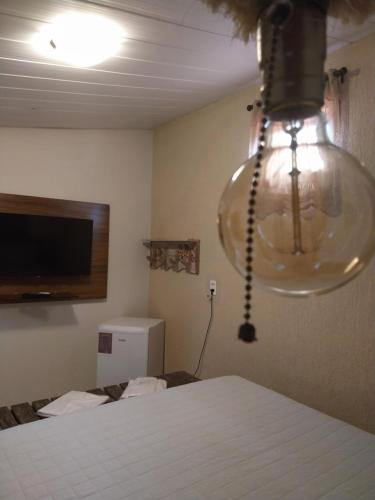 a room with a bed and a light hanging from the ceiling at Suítes Pirenópolis Piri in Pirenópolis