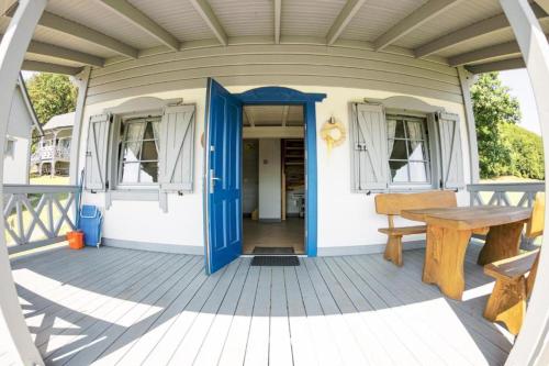 une terrasse couverte avec une porte bleue et une table en bois dans l'établissement Domki pod Kapeluszem nad jeziorem Patulskim,Kaszuby z opcją balii, à Pierszczewo