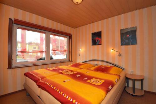 sypialnia z dużym żółtym łóżkiem i oknem w obiekcie Ferienhaus-Hellmich w mieście Scheibe-Alsbach