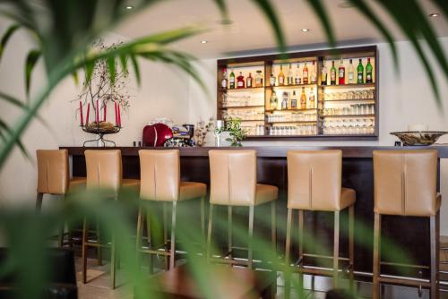 a bar with brown chairs and a counter with bottles at Hotel Regina in Serfaus