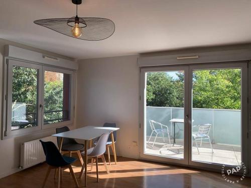 - une salle à manger avec une table, des chaises et des fenêtres dans l'établissement studio récent de 39 m2 meublé, à Créteil