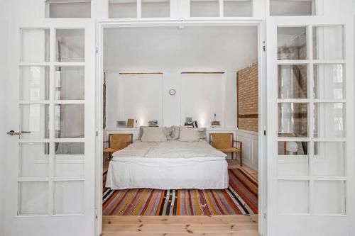 a bedroom with a bed with white sheets and windows at H.C. Andersens hang around in Copenhagen