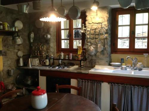 een keuken met een tafel, een wastafel en een aanrecht bij Casale La Selva Cottege grande in Piano Porlezza