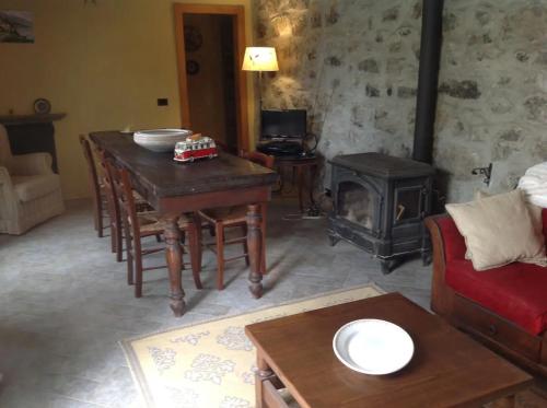 sala de estar con mesa y estufa de leña en Casale La Selva Cottege grande, en Piano Porlezza