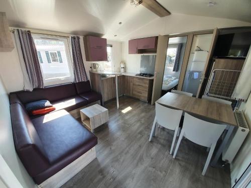 ein Wohnzimmer mit einem Sofa und einem Tisch sowie eine Küche in der Unterkunft Ferienpark Auf dem Simpel - Mobilheim 1 in Soltau