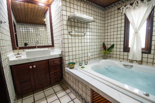 uma casa de banho com uma banheira, um lavatório e um espelho. em Odoiá Maragogi Restaurante e Estalagem em Maragogi