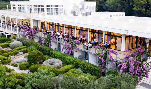 people sitting on the balcony of a building with a garden at Labranda Velaris Village in Supetar