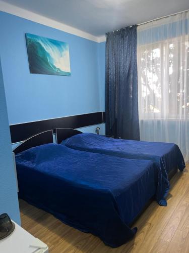 a blue bedroom with a bed and a window at Autopapa in Rustavi