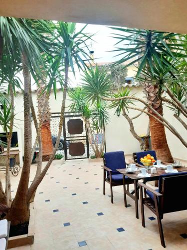a dining room with palm trees and a table and chairs at L'Olivier - Centre village - Au calme in Bessan
