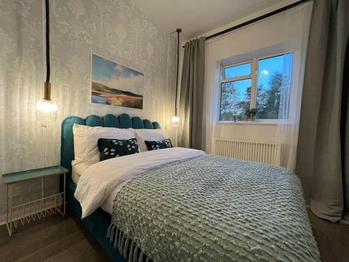 a bedroom with a bed with a blue headboard and a window at Central Welling Flat in Welling