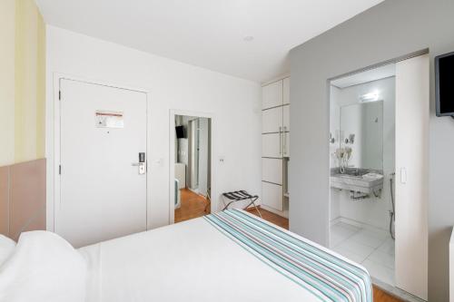 a white bedroom with a bed and a sink at Capcana Hotel Jardins in Sao Paulo