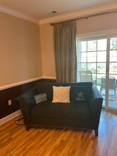 a living room with a green couch in front of a window at Tranquil 3BR Condo in Magnolia Pointe near Myrtlewood Golf Resort in Myrtle Beach