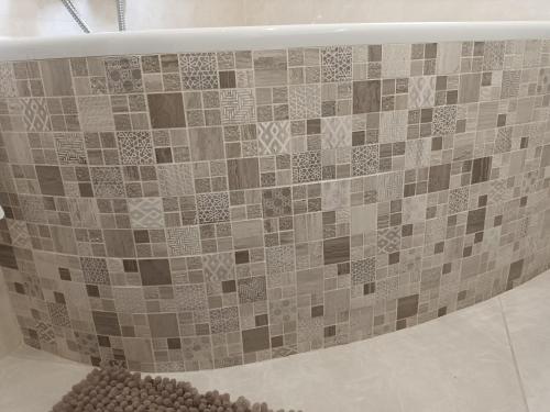 y baño con bañera y pared de azulejos. en Maison rez-de-chaussée, en Livry-Gargan