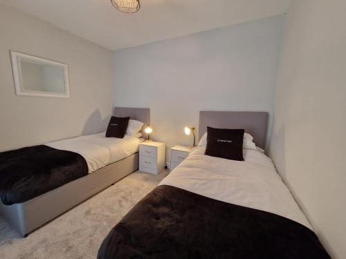 two beds in a small room with two lamps at 4 Bedroom house in Merthyr Tydfil. Near Brecon Beacons National Park in Dowlais